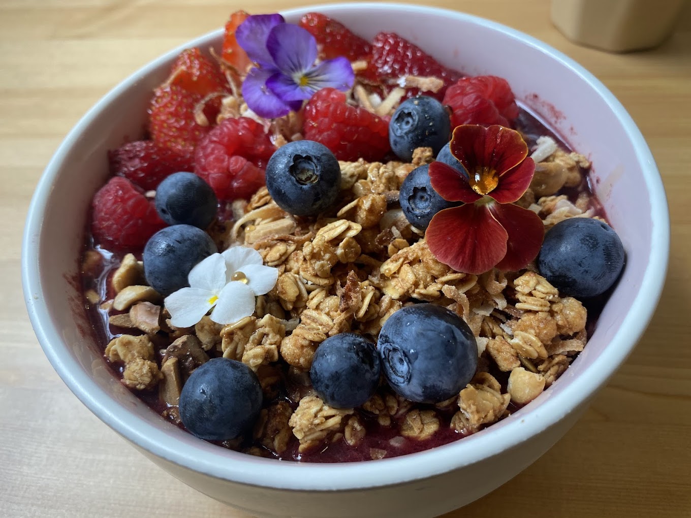 Superfood acai bowl with granola, berries and edible flowers at The Foliage Cafe